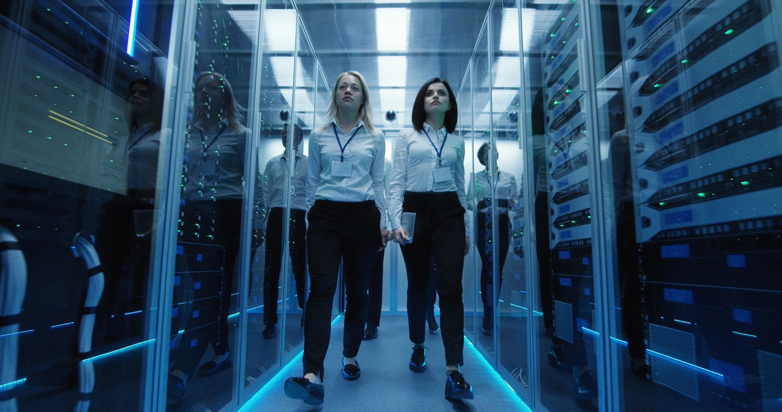 Workers in a data center walking between rows of server racks
